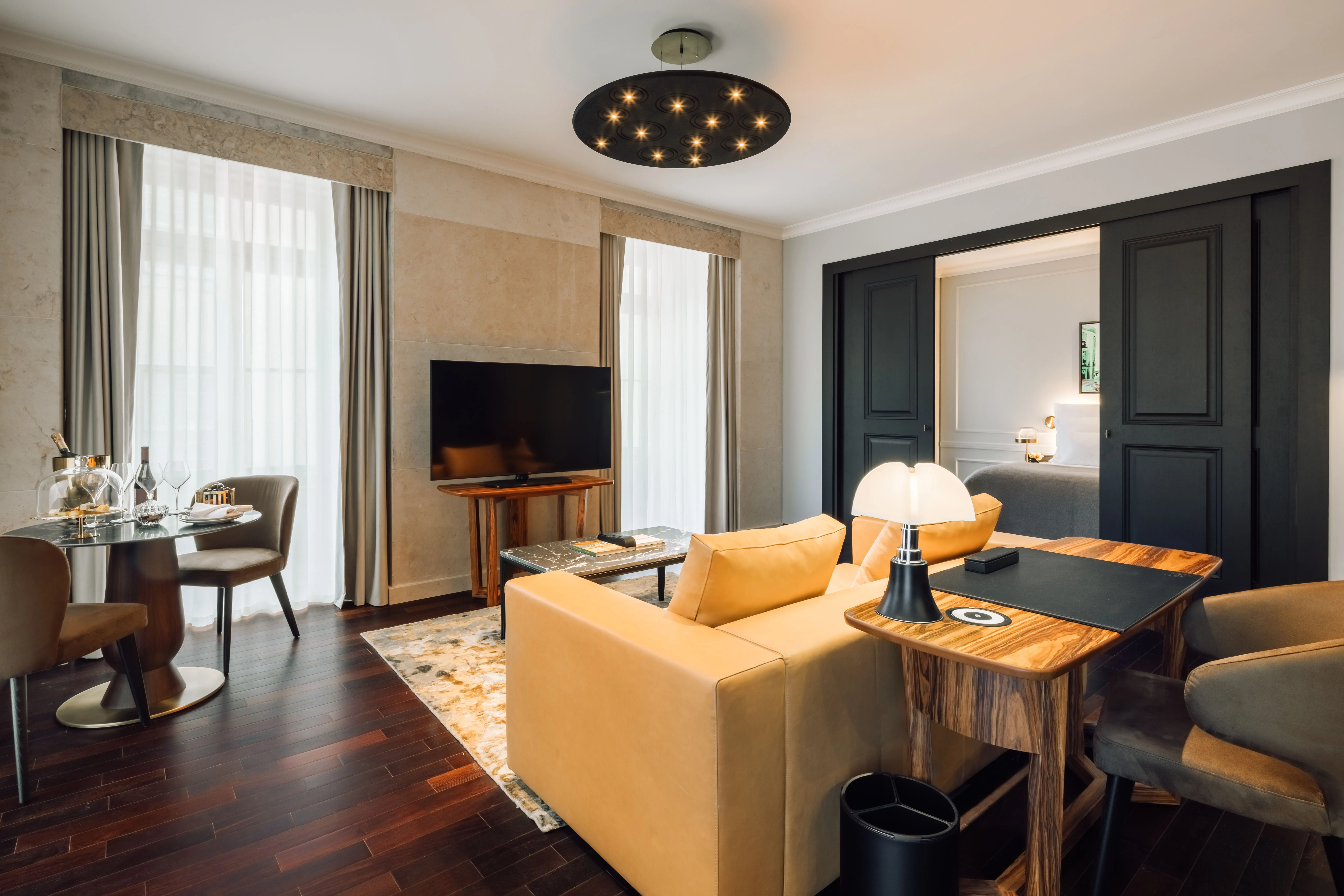 Wohn- und Essbereich einer Suite mit gelbem Sofa und dunklem Holzboden.